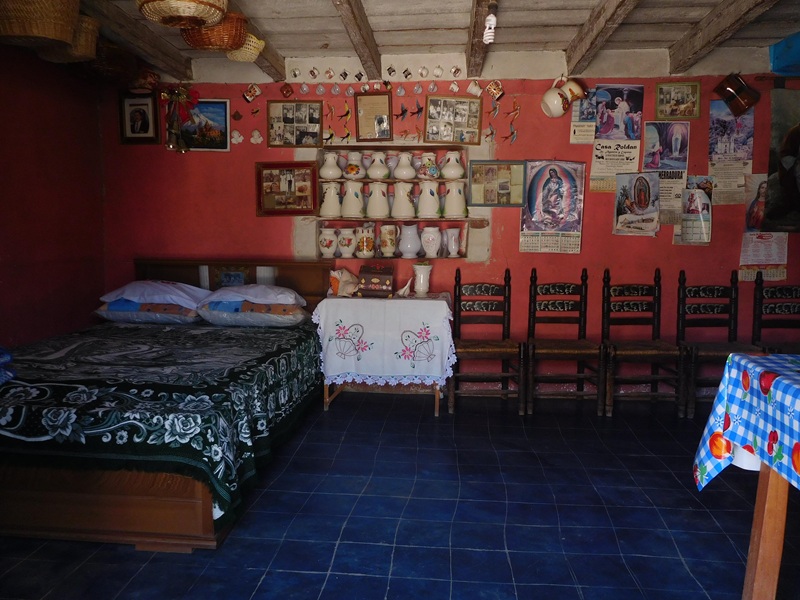 La cama, la mesa y el altar con
imágenes religiosas en el cuarto de dormir