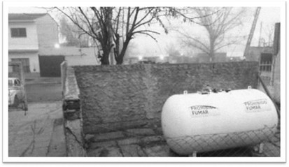 
Fotograf&iacute;a tomada desde la entrada de la escuela donde se observa el contenedor de gas rodeado por un muro o pared
