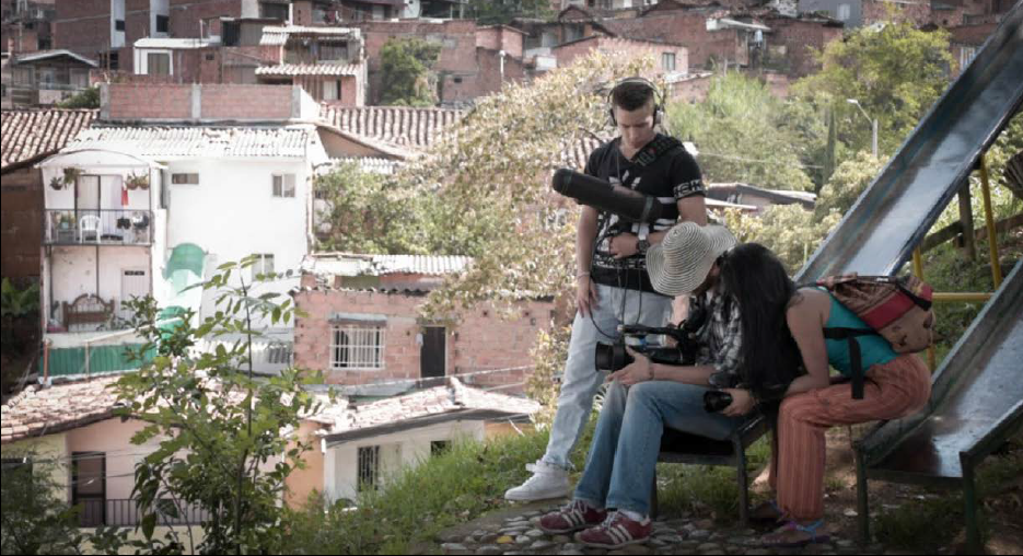 Juan Rubio. Mileidy, Christian y el director de sonido, reunidos con una cámara de video en el parque del barrio Sufre de Medellín, 2019, fotografía.